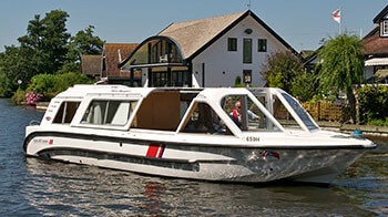 A man cruising on the Norfolk Broads on board a rented boat